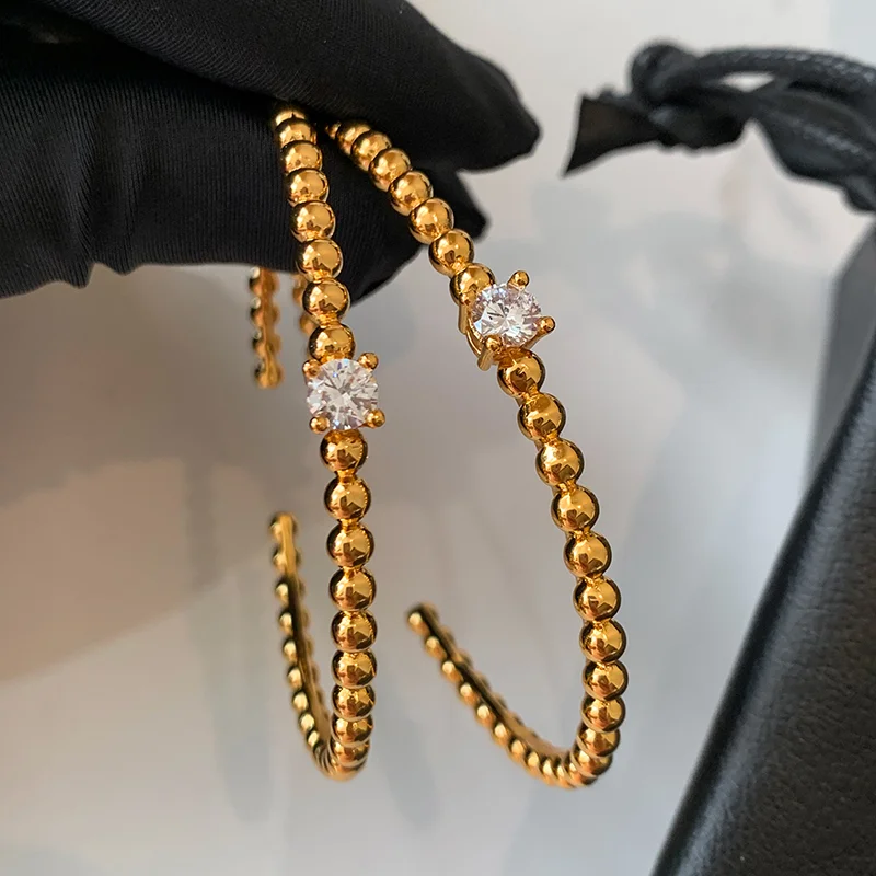 Gold beaded hoop earrings made of brass with a cubic zirconia stone, high-polish finish and anti-tarnish vacuum electroplating.