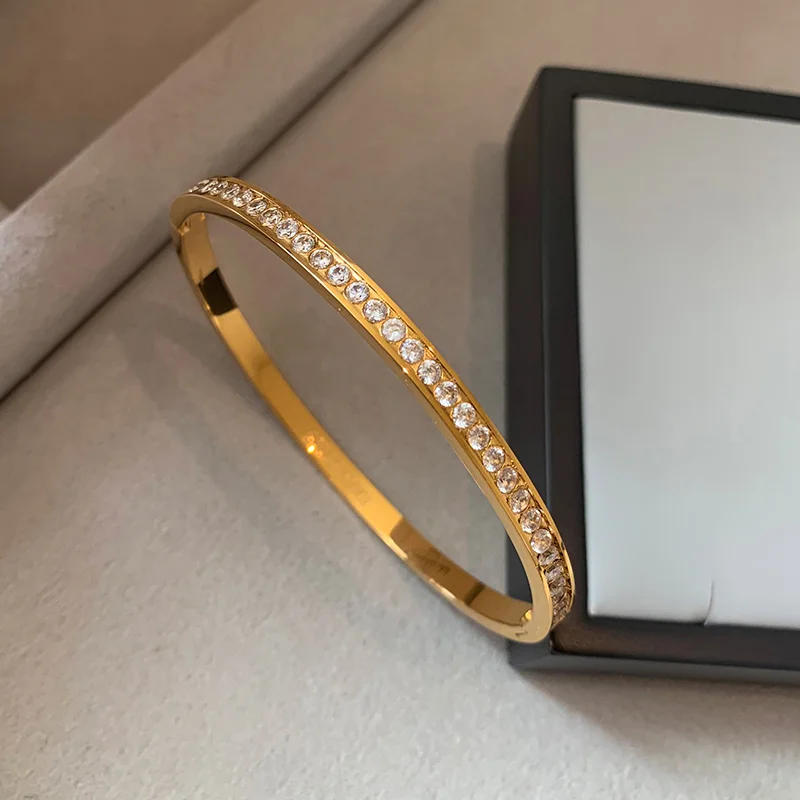 Starry sky designed diamond-embedded gold bangle, made of solid gold (or gold-plated) with zircon decorations, displayed on light-colored fabric next to a jewelry box