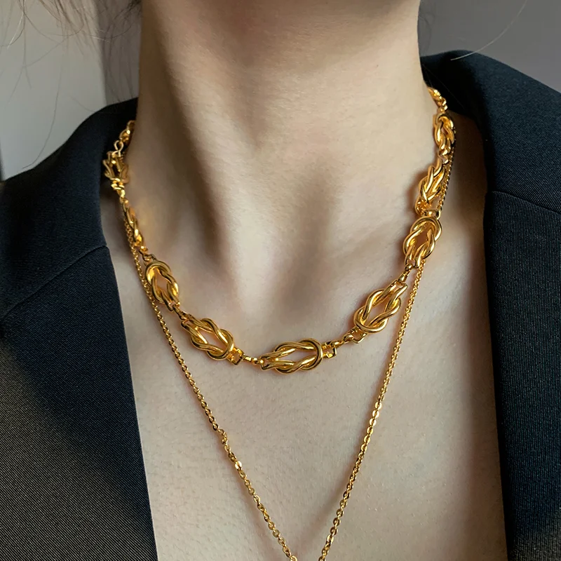Close-up of a stylish gold necklace, featuring linked chain design, worn by a model.